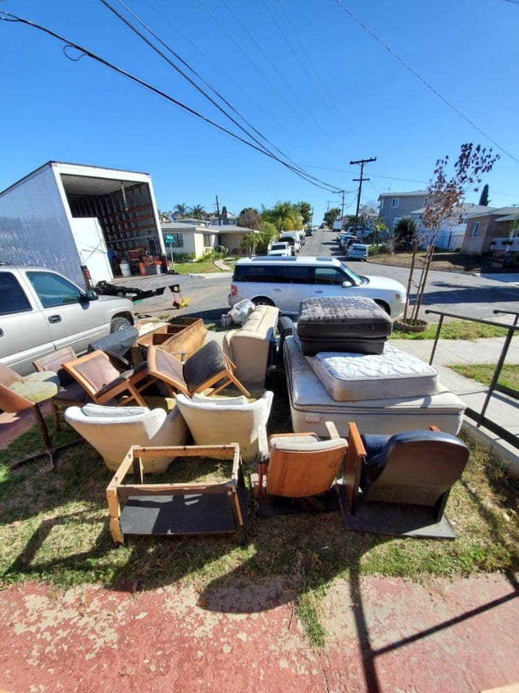 Collection of discarded furniture, including chairs and mattresses, on a residential street.