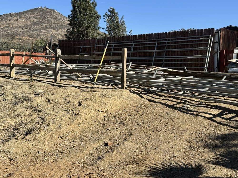Construction site with stacked metal materials and a dirt area under clear blue sky.